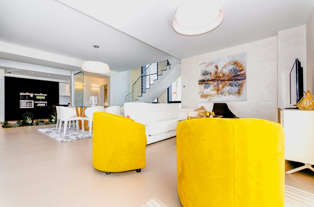 Bright Spanish living and dining area with yellow armchairs and tiled flooring
