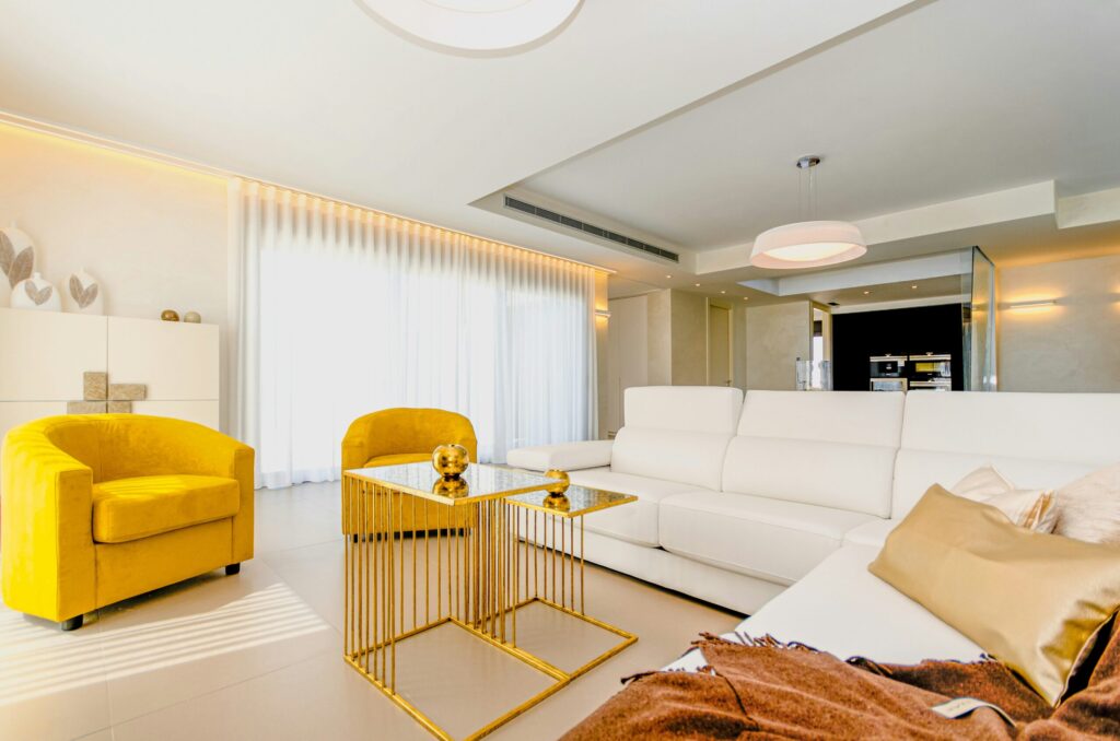 Warm contemporary Spanish lounge with white sofa and golden armchairs